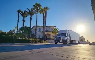 a professional moving truck from team chodorow, parked in front of a sunny san diego residence, symbolizes reliability and excellence in relocation services with a backdrop of palm trees and a clear blue sky.