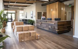 a welcoming san diego moving company office exudes trust and transparency, featuring a spacious reception area bathed in soft, natural light, highlighted by moving boxes neatly packed with protective materials and a friendly consultant attentively engaging with clients.